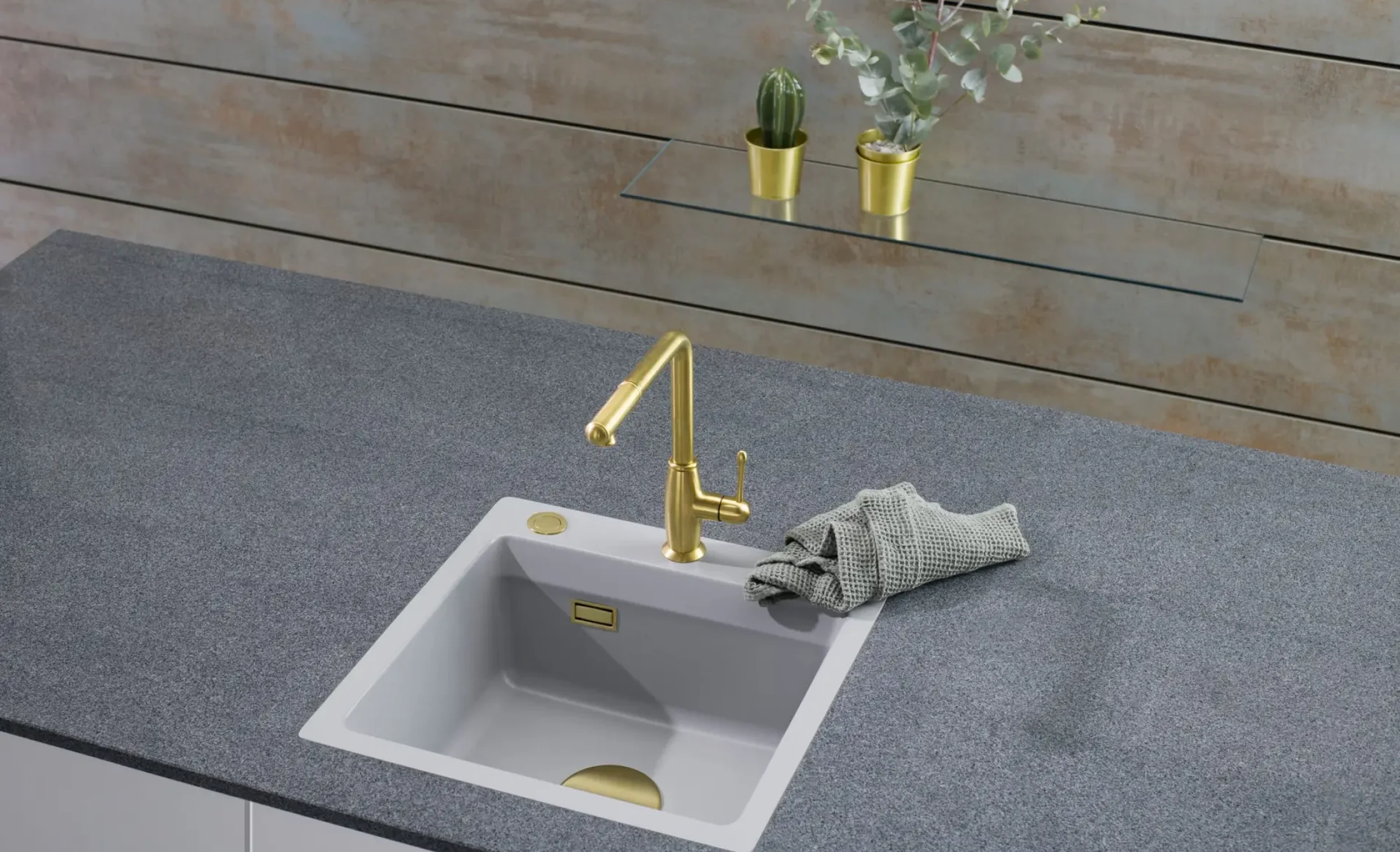 Weiße Spüle mit goldfarbener Armatur in einer grauen Arbeitsplatte